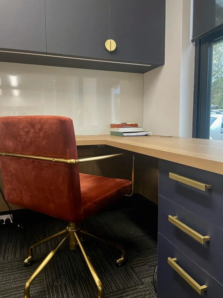 A clean and organized office with two desks placed by a window, enhancing the workspace with natural light